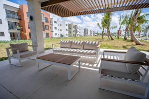 a patio with two chairs and a couch and a table at Apartamento con piscina, gimnasio y acceso a playa in Punta Cana