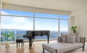 a living room with a piano in front of a large window at Luxury apartments in Los Angeles