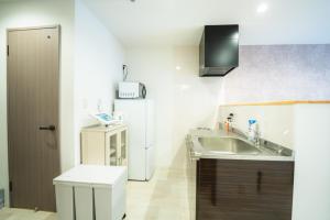 a kitchen with a sink and a refrigerator at 貸切アパートメントSign Palace サインパレス in Kagoshima