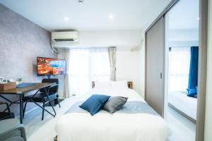a bedroom with a bed and a table and a desk at 貸切アパートメントSign Palace サインパレス in Kagoshima