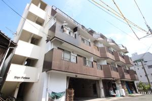 a white building with brown balconies on a street at Sign Palace サインパレス in Kagoshima