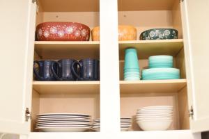a cupboard filled with plates and bowls at Mile to Beach! Fully Fenced Private SoCal Cottage in Oceanside