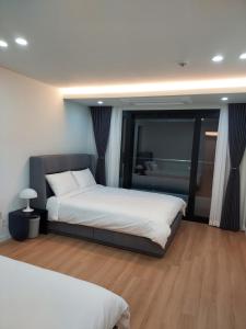 a bedroom with two beds and a large window at Almare Woljeong in Jeju