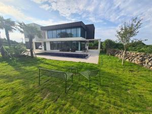 a house with two benches in the grass at Almare Woljeong in Jeju