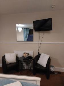 ein Wohnzimmer mit 2 Stühlen und einem Flachbild-TV in der Unterkunft Lynbar guesthouse in Blackpool