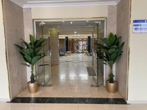 einen Flur mit zwei Topfpflanzen in einer Lobby in der Unterkunft فندق حدائق فرسان الفندقية in Ḩumr