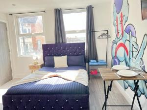 Schlafzimmer mit einem Bett mit blauem Kopfteil und einem Tisch in der Unterkunft Studio Apartments Central London in London