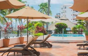 een groep stoelen en parasols naast een zwembad bij one beach street hotel -Beach front Spacious 1BD 1BA fabulous view in Zona Romantic Puerto Vallarta in Puerto Vallarta