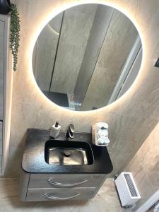 ein Bad mit einem Waschbecken und einem runden Spiegel in der Unterkunft New apartment at 150m from the beaches Easy check in in Juan-les-Pins