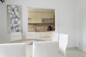a white kitchen with a table and white chairs at Apartments Mare in Banjol