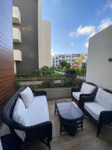 3 sedie e un tavolino da caffè sul balcone di Duplex luxe - Résidence privée - Casablanca/Bouskoura a Bouskoura