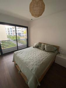 um quarto com uma cama e uma grande janela em Duplex luxe - Résidence privée - Casablanca/Bouskoura em Bouskoura