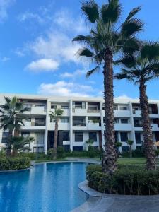 um edifício com palmeiras em frente a uma piscina em Duplex luxe - Résidence privée - Casablanca/Bouskoura em Bouskoura