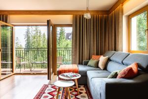 a living room with a blue couch and a balcony at Apartamenty Blisko TATR Zakopane in Zakopane +66 photos