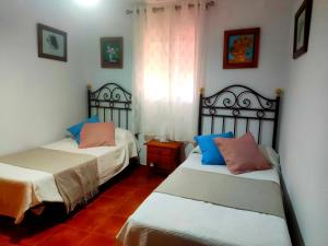 2 Betten in einem Zimmer mit blauen und rosa Kissen in der Unterkunft La Casa del Naturalista in El Bosque