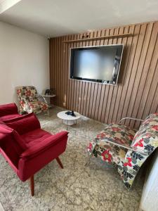 a living room with two chairs and a tv on a wall at Hotel Uirapuru in Alexânia