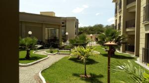 a courtyard with palm trees and a building at Flat_Quartie_aldeia_das_aguas in Barra do Piraí