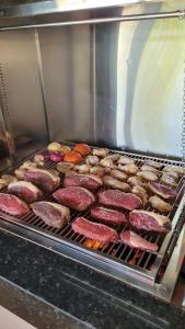 een grill met verschillende soorten vlees en andere voedingsmiddelen bij Pousada Chez bubônia in Novo Acordo