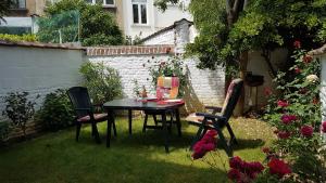 een tafel en stoelen in een tuin met rozen bij Modern duplex with garden in Brussel