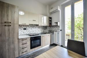 une cuisine avec des placards blancs et une grande fenêtre dans l'établissement Benvenuti Casa Leo - Elegante Appartamento, à Turin