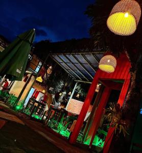 a restaurant with green chairs and an umbrella at night at Pousada Crocodilo Caraíva in Caraíva
