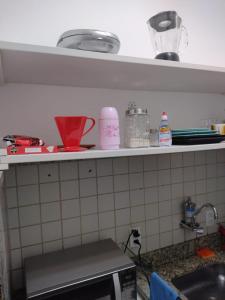 a kitchen with a sink and a shelf with dishes at Apartamento aconchegante no Sudoeste in Brasília