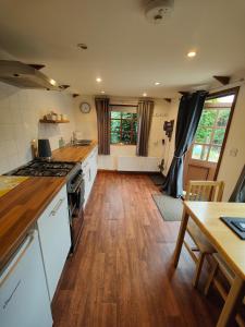 uma cozinha com electrodomésticos brancos e piso em madeira em The Garden Lodge em Llynclys