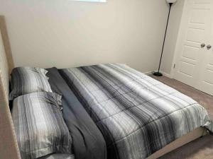 a bed with a striped comforter in a bedroom at Homestay in Winnipeg
