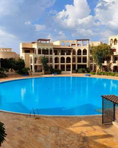 a large blue swimming pool in front of a building at Flat One room apartment in talabay aqaba in Al Burj