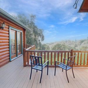 two chairs sitting on the deck of a cabin at Log cabin oasis with spectacular views & stargazing in Mariposa