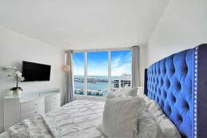 a bedroom with a blue bed and a large window at Bay Watch Penthouse! Direct Water Views! in Miami