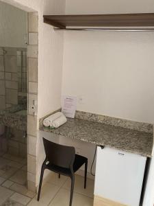 a bathroom with a counter with a chair and a sink at Hotel Uirapuru in Alexânia