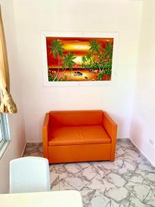 an orange couch in a room with a painting on the wall at Apartamentos felix Las terrenas in Las Terrenas
