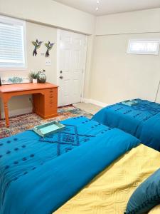 1 dormitorio con 2 camas azules y escritorio en Minutes to the River Walk and the Alamo Pet Friendly Sleeps 8!, en San Antonio
