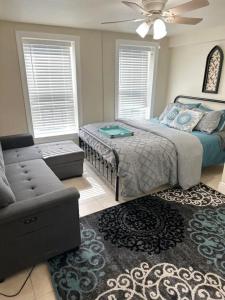 a bedroom with a bed and a couch and a fan at Minutes to the River Walk and the Alamo Pet Friendly Sleeps 8! in San Antonio