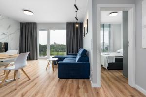 a living room with a blue couch and a bedroom at Riverside Apartments by KRAMM in Poznań