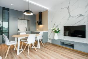 a kitchen and dining room with a wooden table and white chairs at Riverside Apartments by KRAMM in Poznań