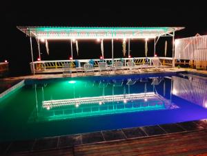a swimming pool at night with chairs around it at Pan guest house in Ban Donsôm