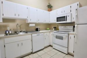 una cocina con armarios blancos y electrodomésticos blancos en Nomad Retreat King Bed Boutique Condo w Garage, en Gainesville