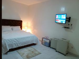 ダカールにあるAppartement 3 chambres toutes climatisées à virageのベッドと壁にテレビが掛かった寝室