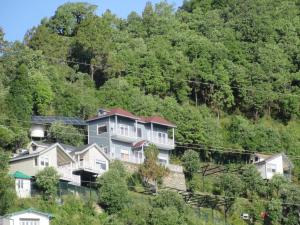 un groupe de maisons sur une colline plantée d'arbres dans l'établissement The Great Escape Homestay, Gagar, Nainital, à Rāmgarh