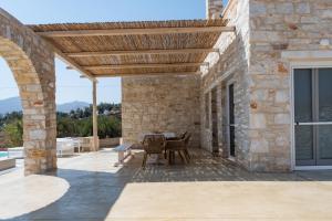 eine Terrasse mit einer hölzernen Pergola und einem Tisch in der Unterkunft Aegean Feelings in Piso Livadi