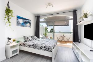 a white bedroom with a bed and a large window at aloha Garden in Adeje