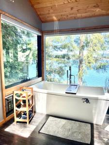 a bath tub in a room with a large window at The Salish Sunset Cabin in Pender Island