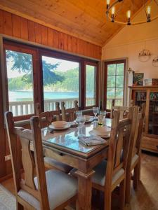 a dining room with a table and chairs and windows at The Salish Sunset Cabin in Pender Island