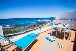 balcón con mesa, sillas y vistas al océano en Suite Ocean Rooms, en Arrieta