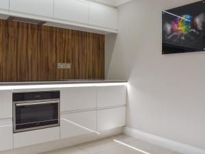 a kitchen with white cabinets and a tv on the wall at Hollies Cottage 3 - Ukc4522 in Martock