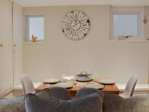 mesa de comedor con sillas y reloj en la pared en Treadle Cottage en Kirkby Lonsdale