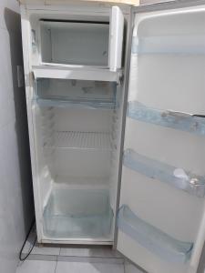 an empty refrigerator with its door open in a kitchen at Pousada do Joaquimxdarc in Natal