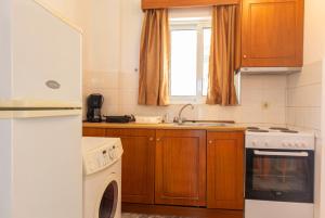 cocina con armarios de madera y lavavajillas blanco en Seaheaven houses A2, en Koroni